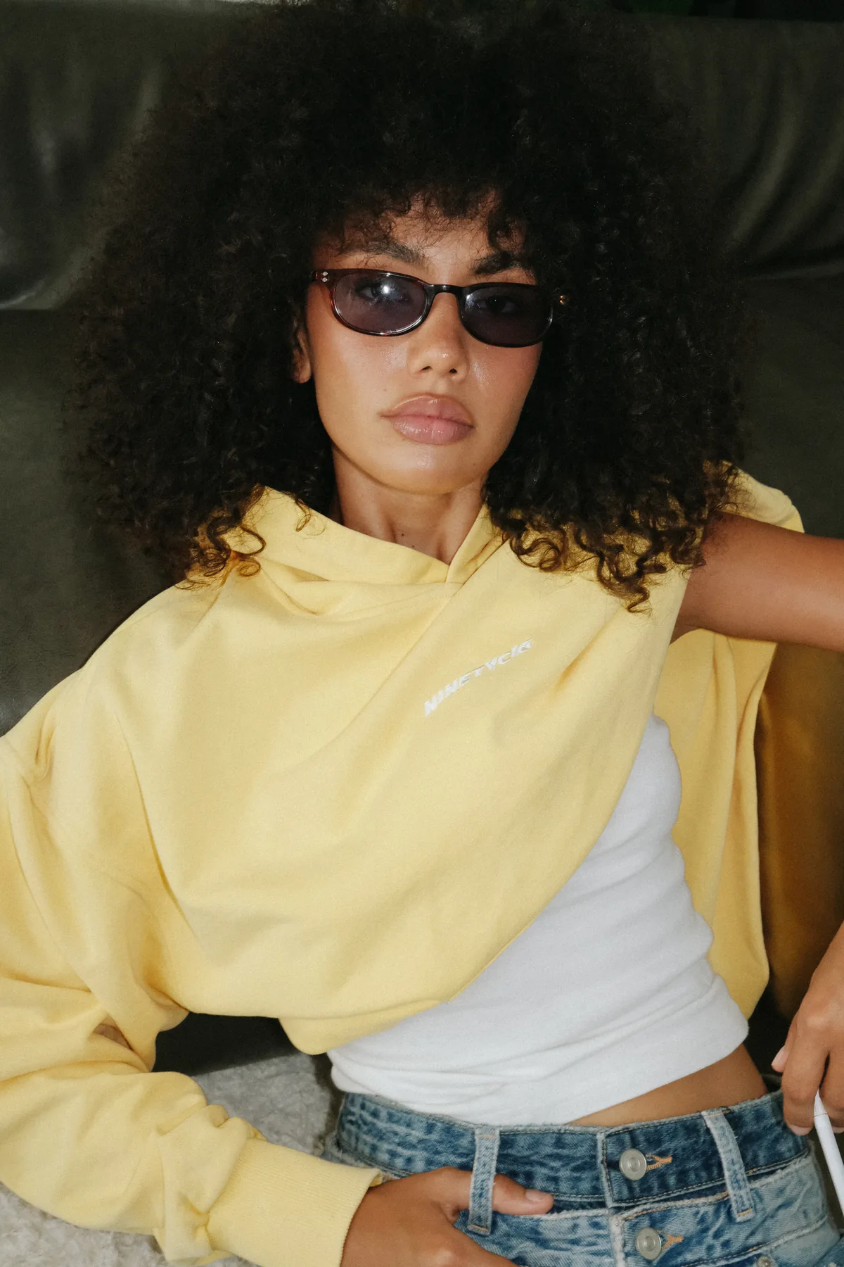 Model in sunglasses wearing a yellow sweatshirt